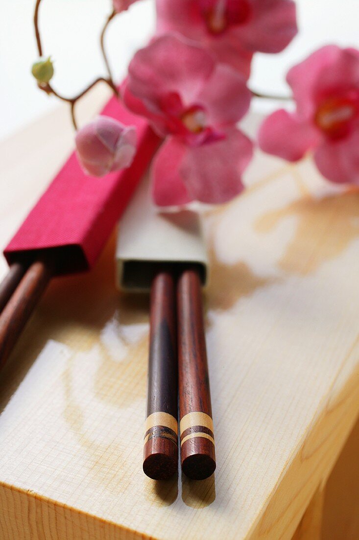Japanese chopsticks and flowers on wooden board