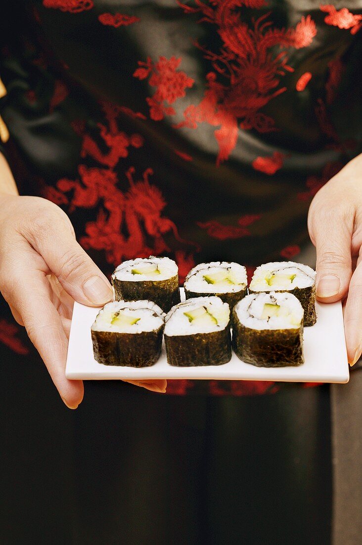 Hände servieren Maki-Sushi
