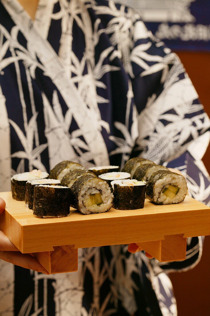 Person im Kimono serviert Maki-Sushi