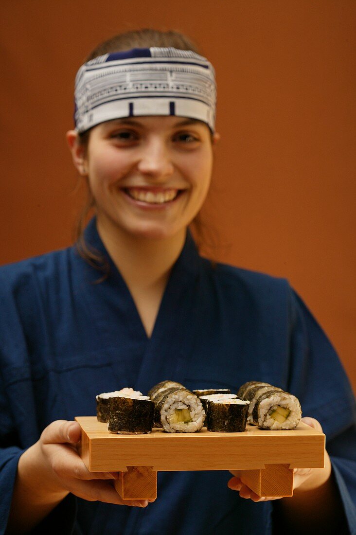 Frau im blauen Kimono serviert Maki-Sushi