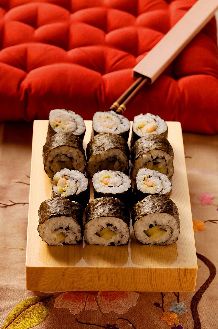 Maki-Sushi-Platte vor rotem Kissen