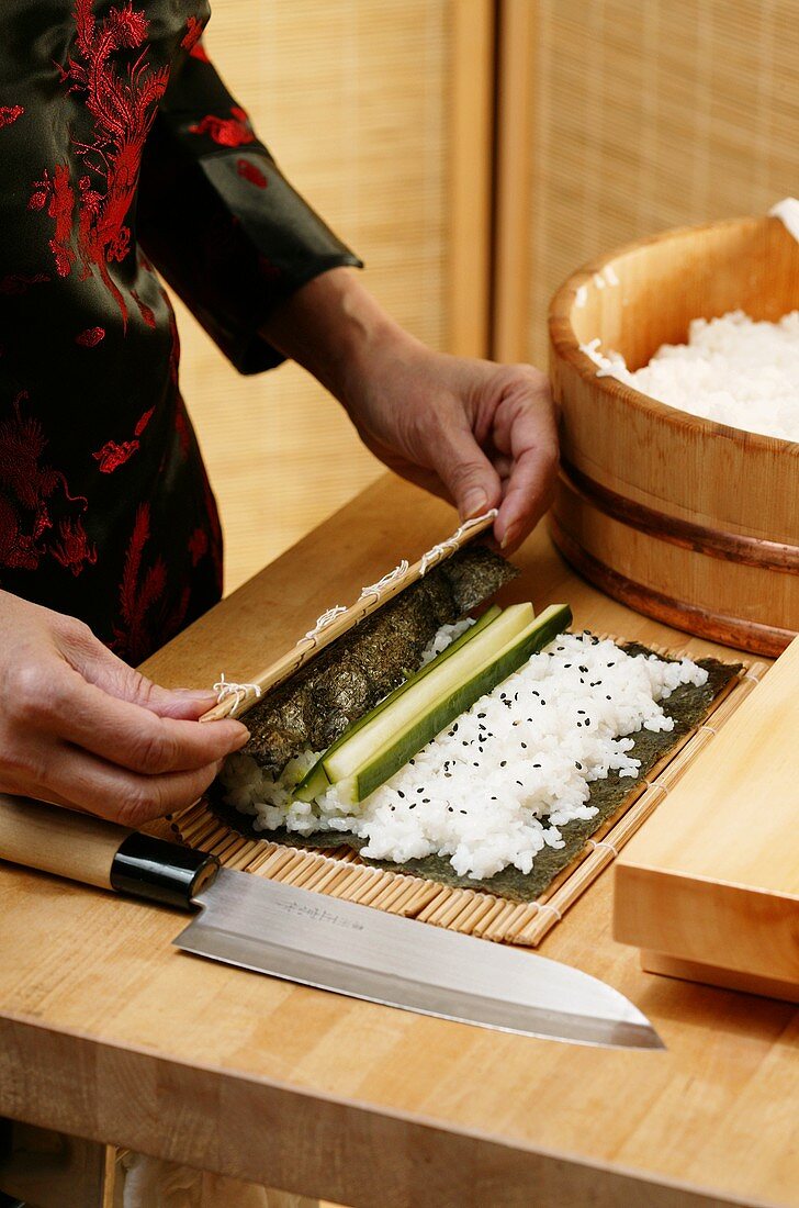 Preparing rolled sushi with cucumber