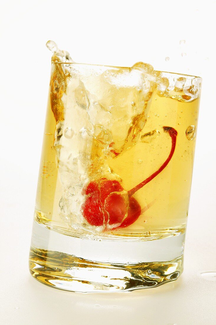Ginger Ale mit Cocktailkirsche spritzt aus dem Glas