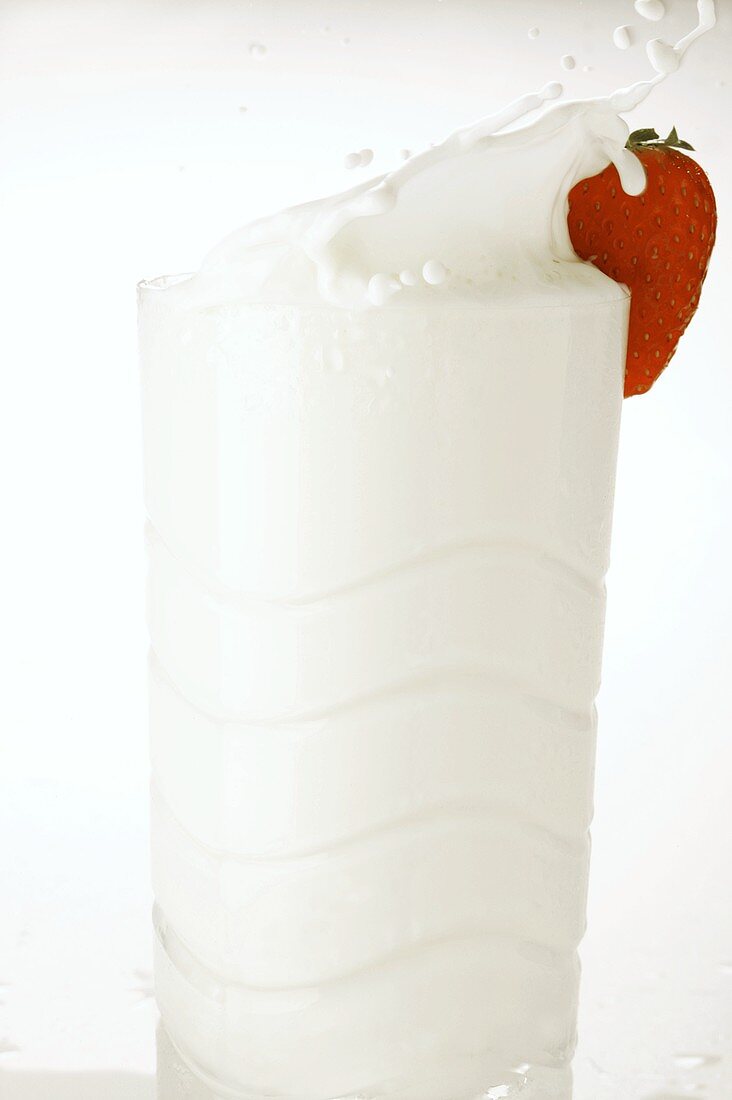 Milk splashing out of glass with strawberry