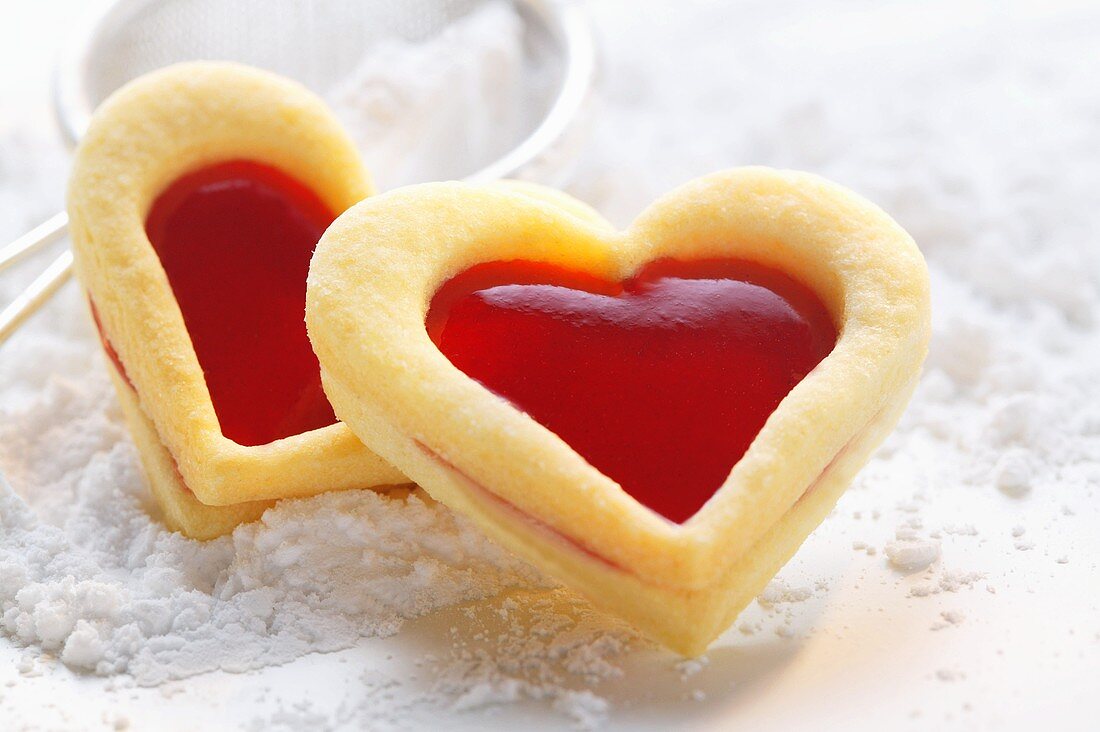 Sweet pastry hearts with raspberry jam on icing sugar