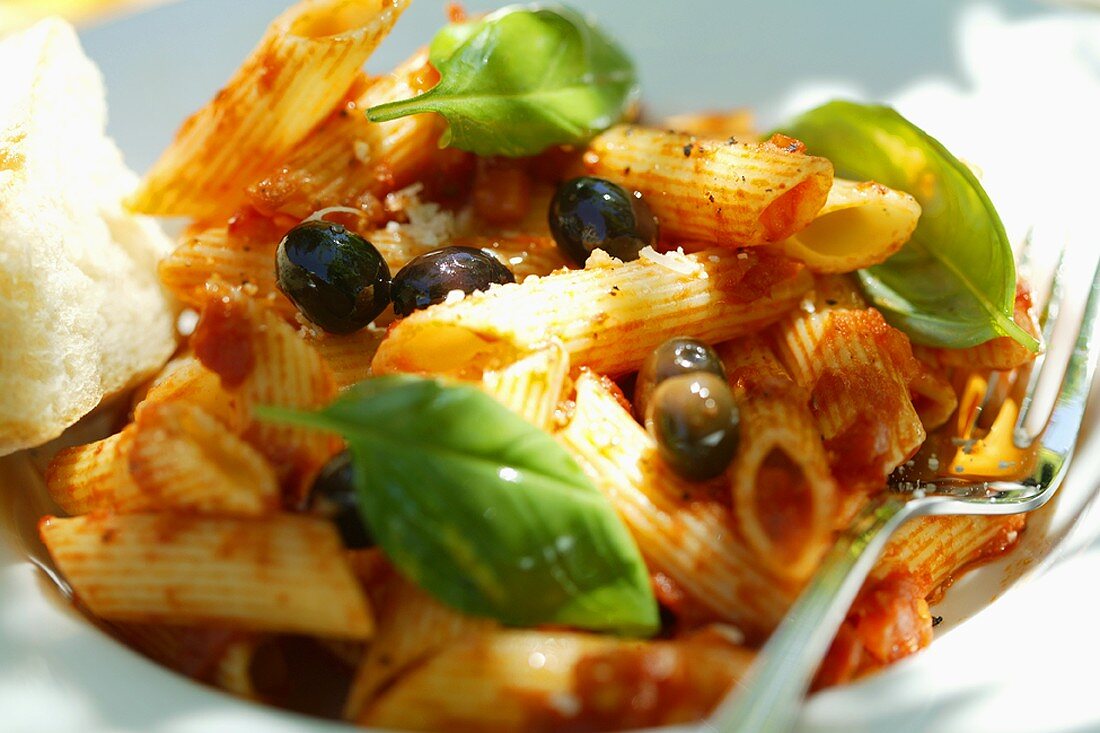 Penne rigate mit Tomatensauce, Oliven und Basilikum