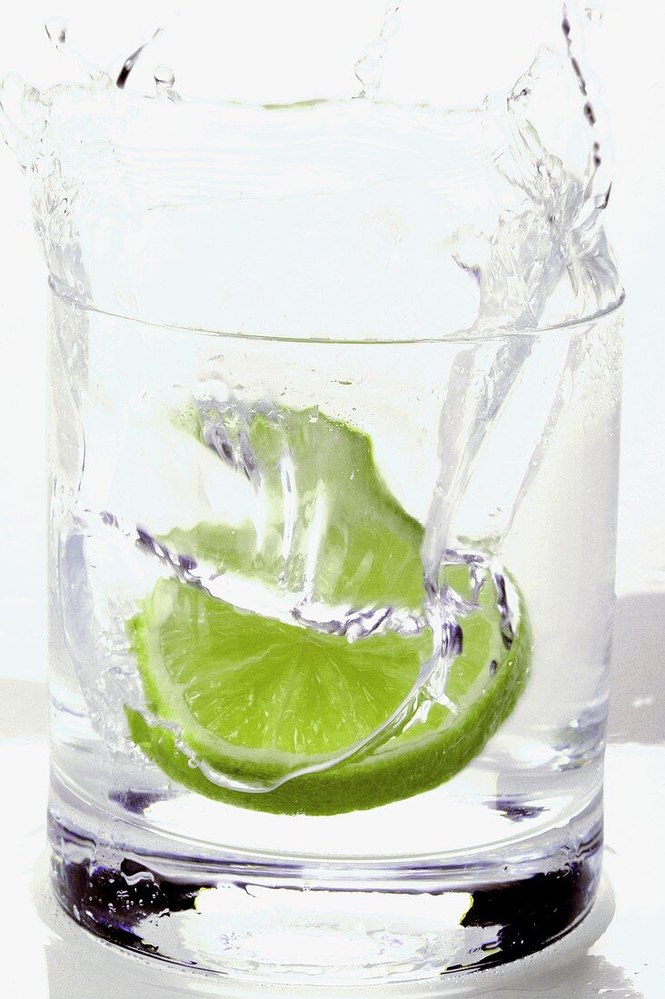 Pouring water into a glass with a slice of lime