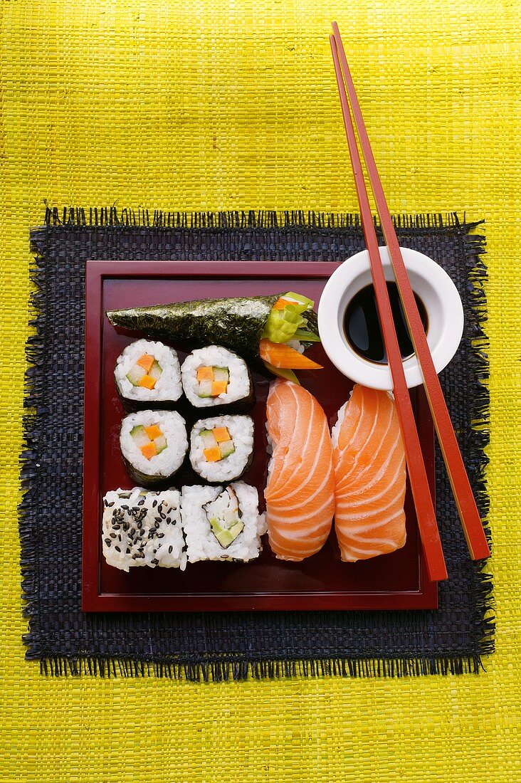 Verschiedene Sushi auf roter Platte; Sojasauce