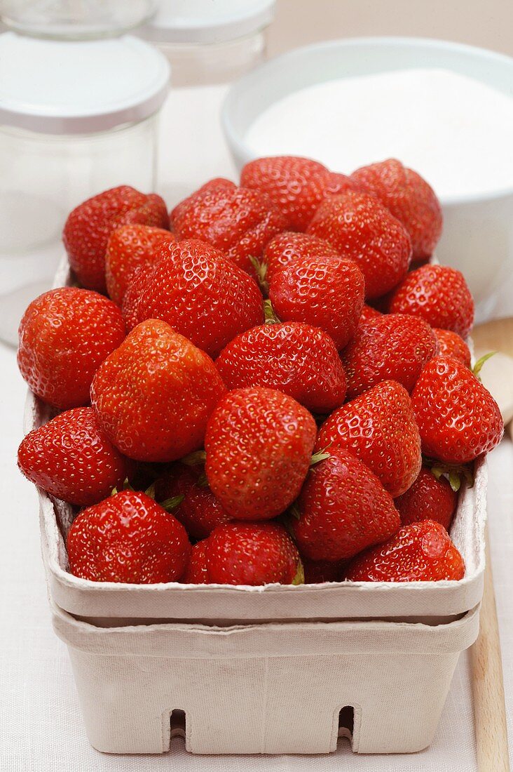 Frische Erdbeeren in Pappschale; Einmachgläser; Zucker