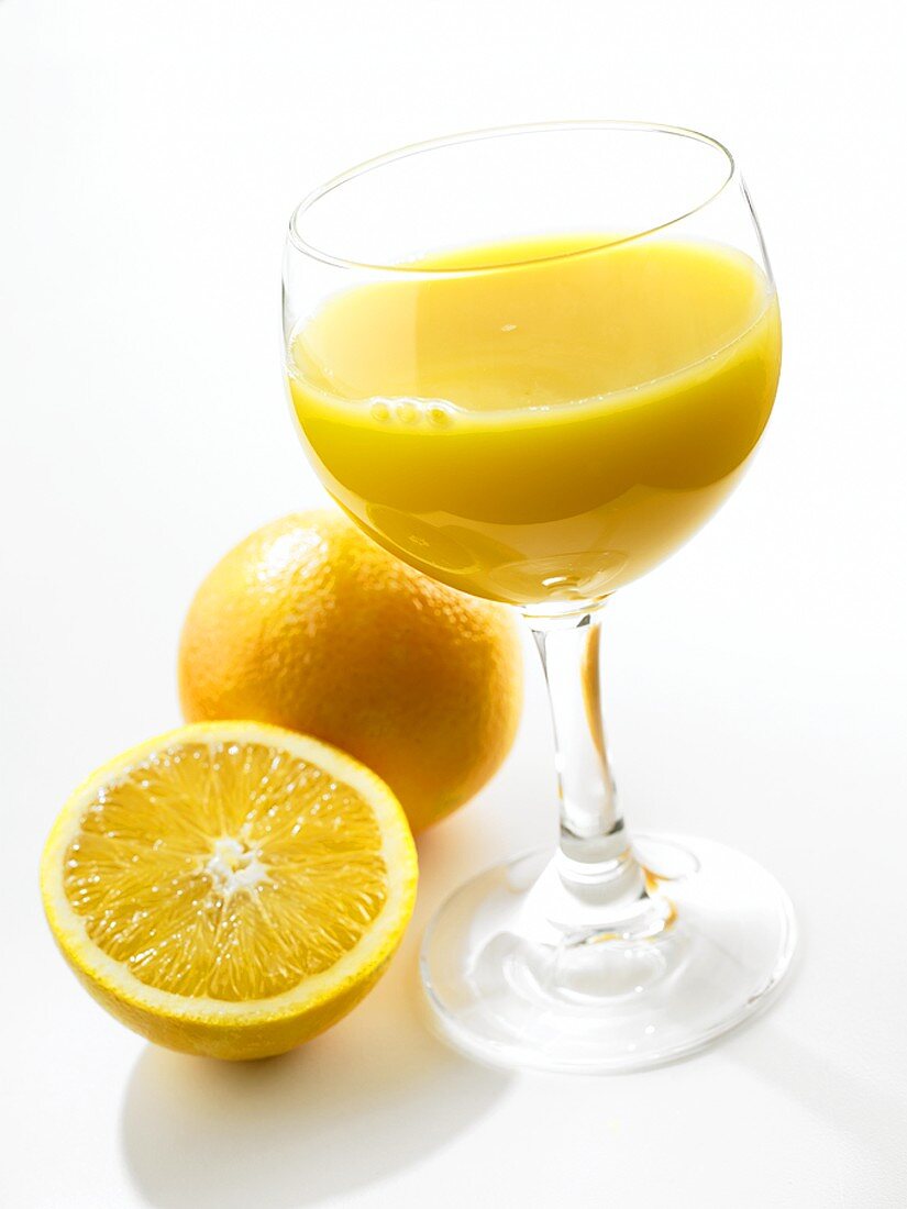 Glass of orange juice and fresh oranges