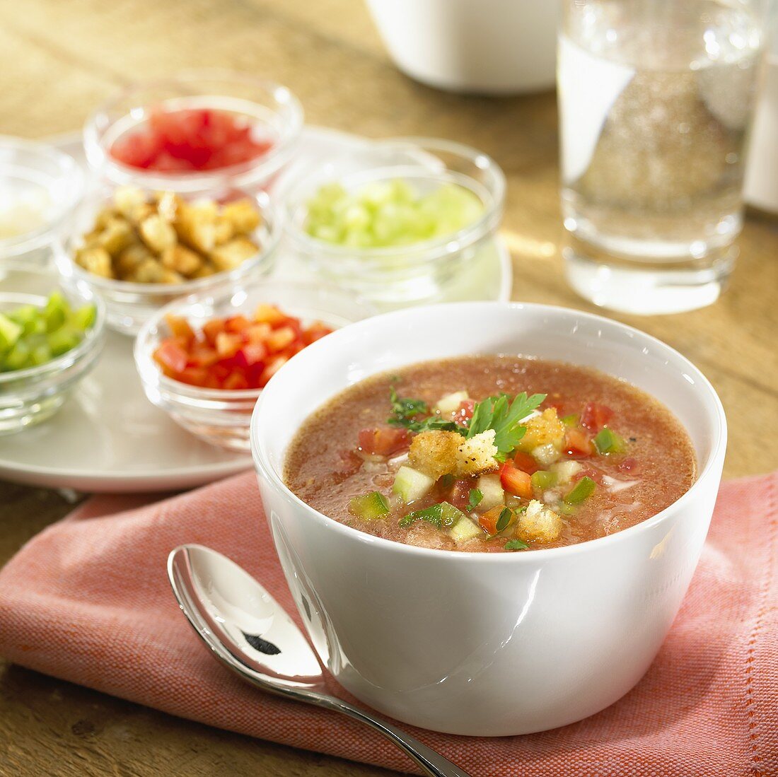 Gazpacho im Suppenschälchen, umgeben von Zutaten