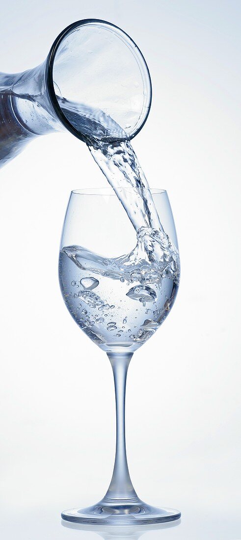 Wasser aus Karaffe in Glas gießen