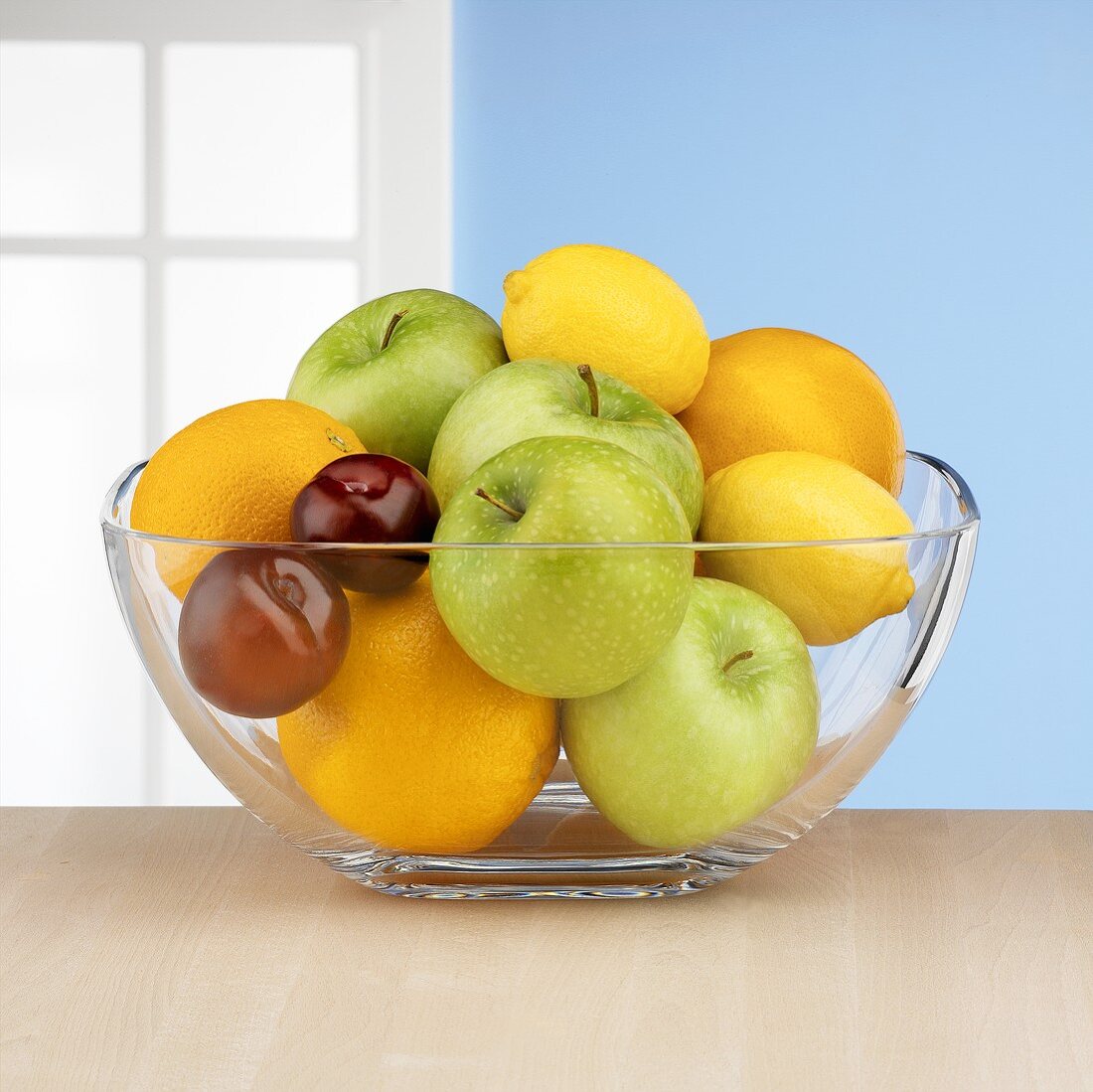 Fresh fruit in glass bowl in front of window