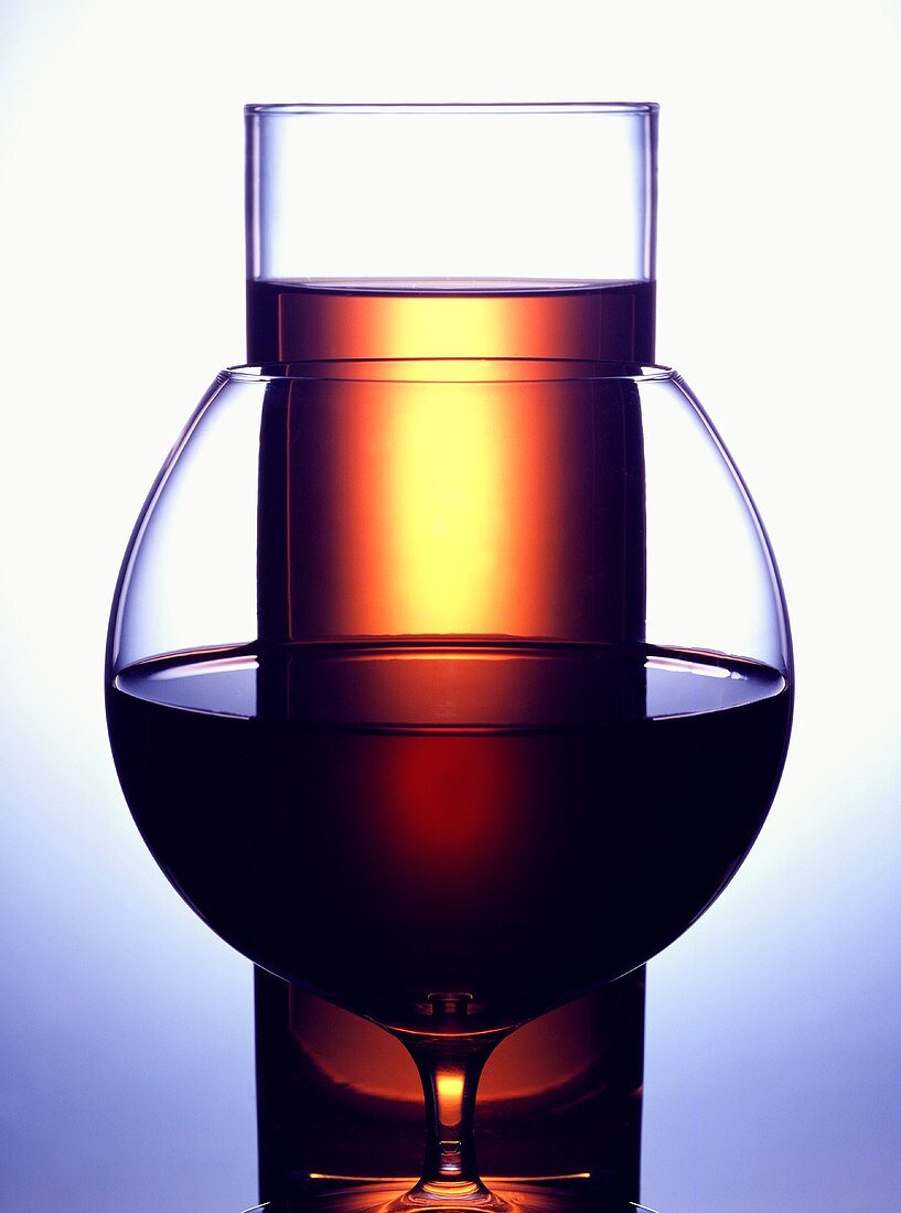 Glass of red wine in front of a glass of apple juice