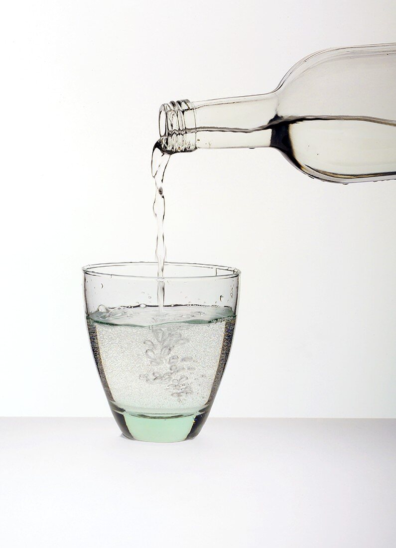 Wasser aus Flasche in Glas gießen