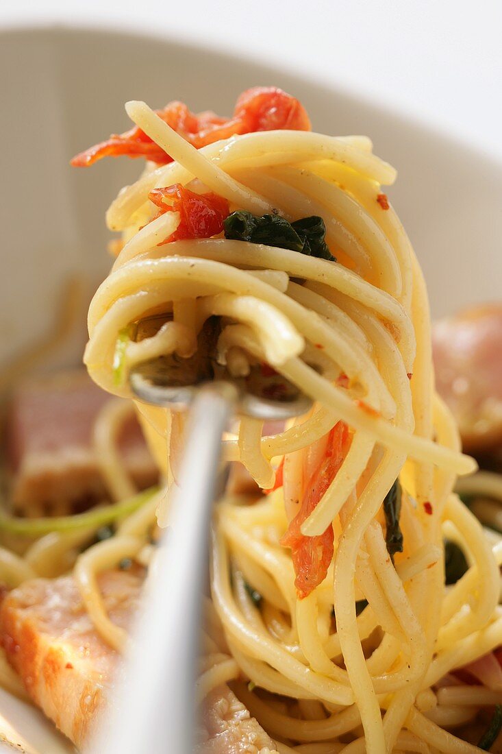 Spaghetti mit Thunfisch, Tomaten und Basilikum auf Gabel