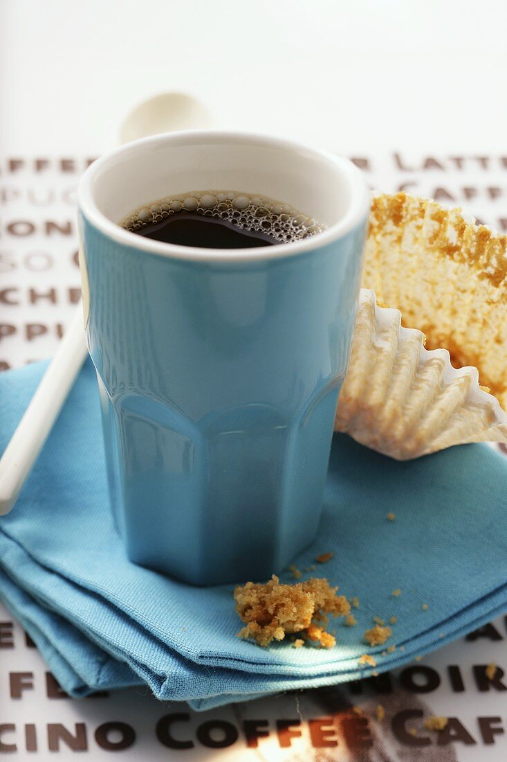Blaue Espressotasse und leeres Muffin-Papierförmchen