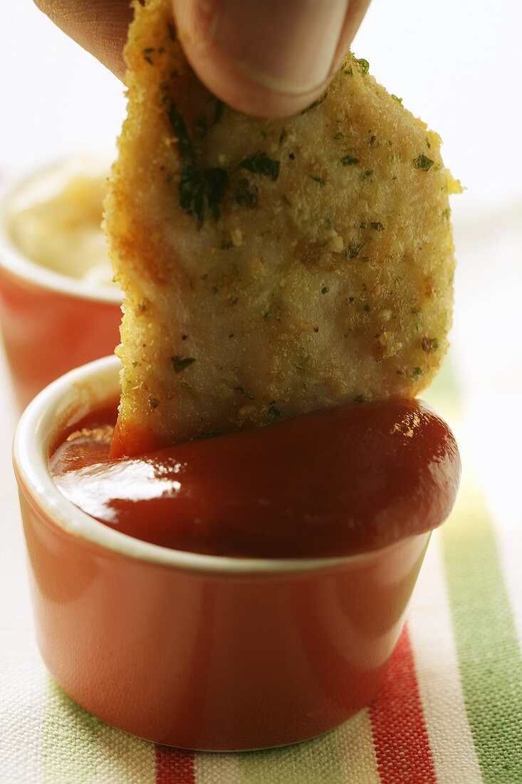 Dipping chicken nugget into ketchup