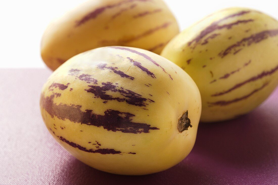 Three pepino melons on purple background