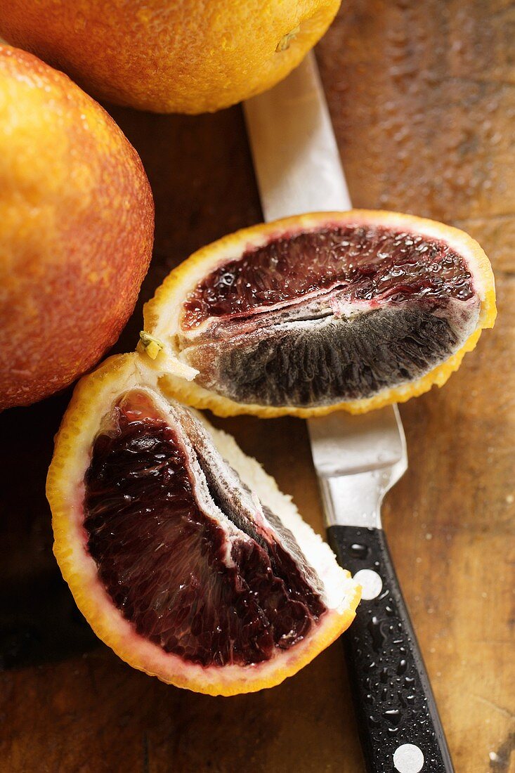 Blood oranges with two wedges on chopping board
