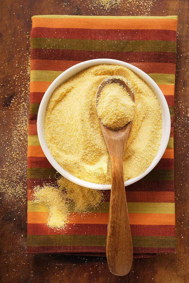 Polenta in Schale mit Holzlöffel auf buntem Tuch