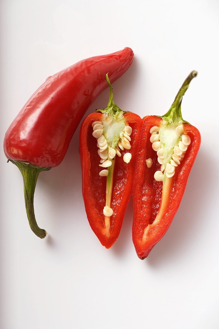 Two red chili peppers, one halved