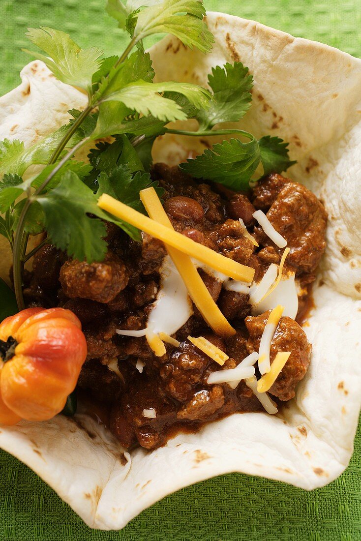 Chili con carne with cheese and sour cream in tortilla shell