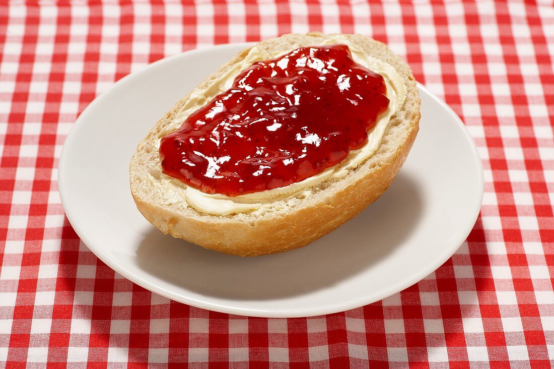 Bread roll with butter and strawberry jam