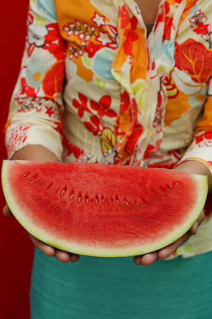 Woman holding slice of watermelon