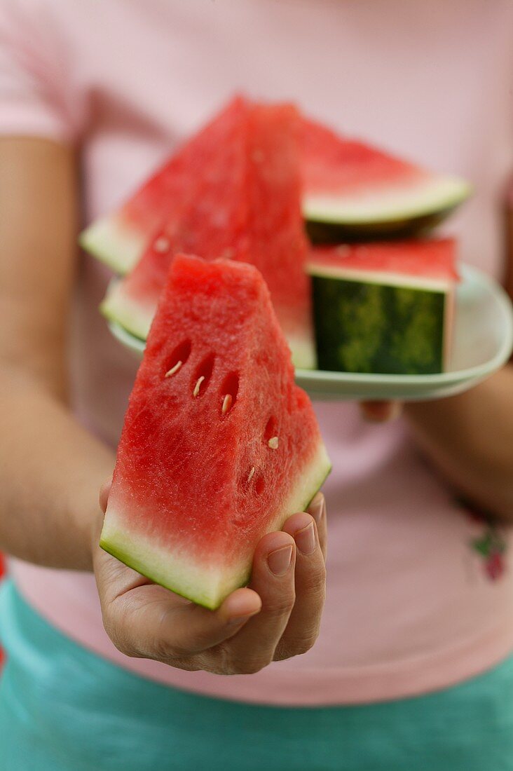 Woman holding wedge of watermelon