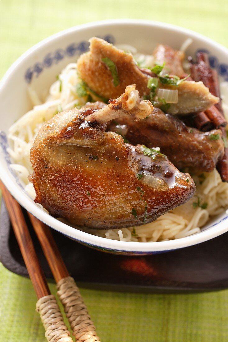 Roast pigeon on noodles in Asian bowl; chopsticks