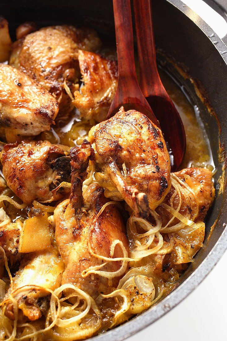 Braised chicken with onions in cast-iron frying pan