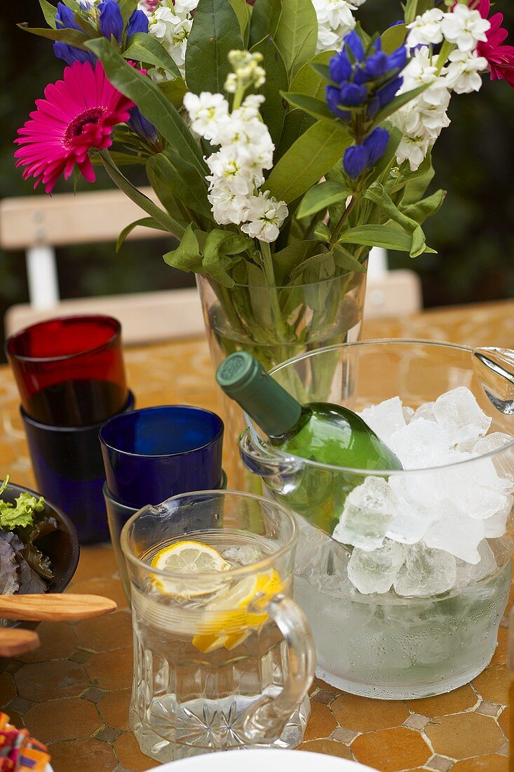 Table with white wine, lemon water, flowers, glasses (outside)