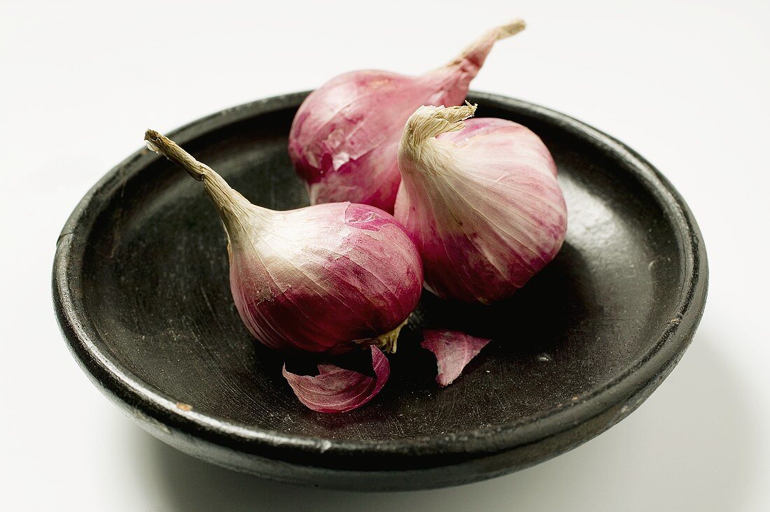 Three red onions in black bowl