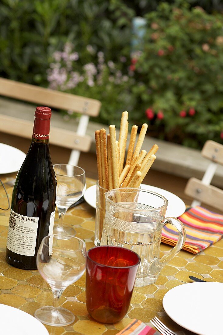 Summery table with red wine and grissini in open air