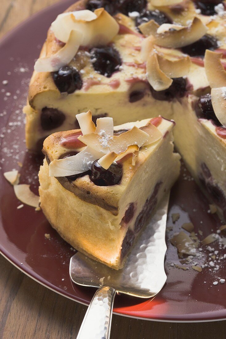 Cheesecake with cherries and coconut shavings, a piece cut