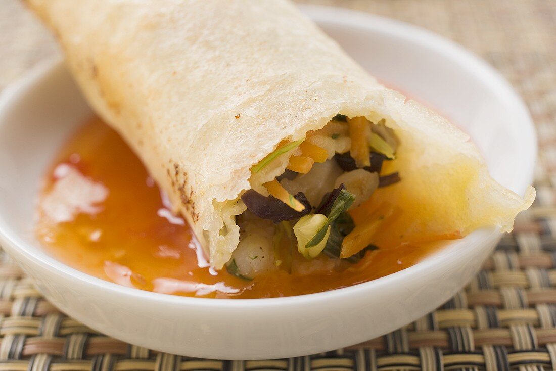 Dipping spring roll in chili sauce
