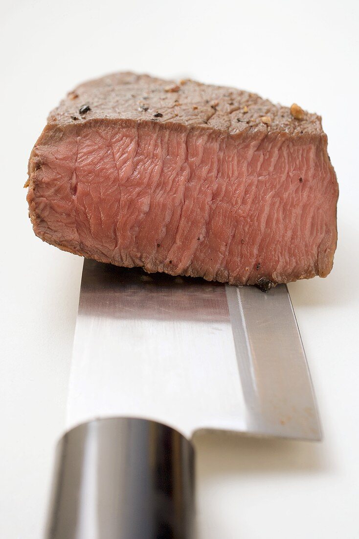 Beef steak, a piece cut off, on Asian knife