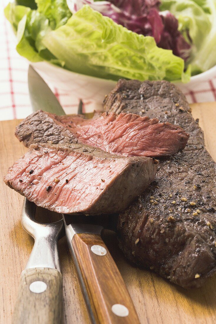 Rindersteaks, teilweise in Scheiben geschnitten, Salat