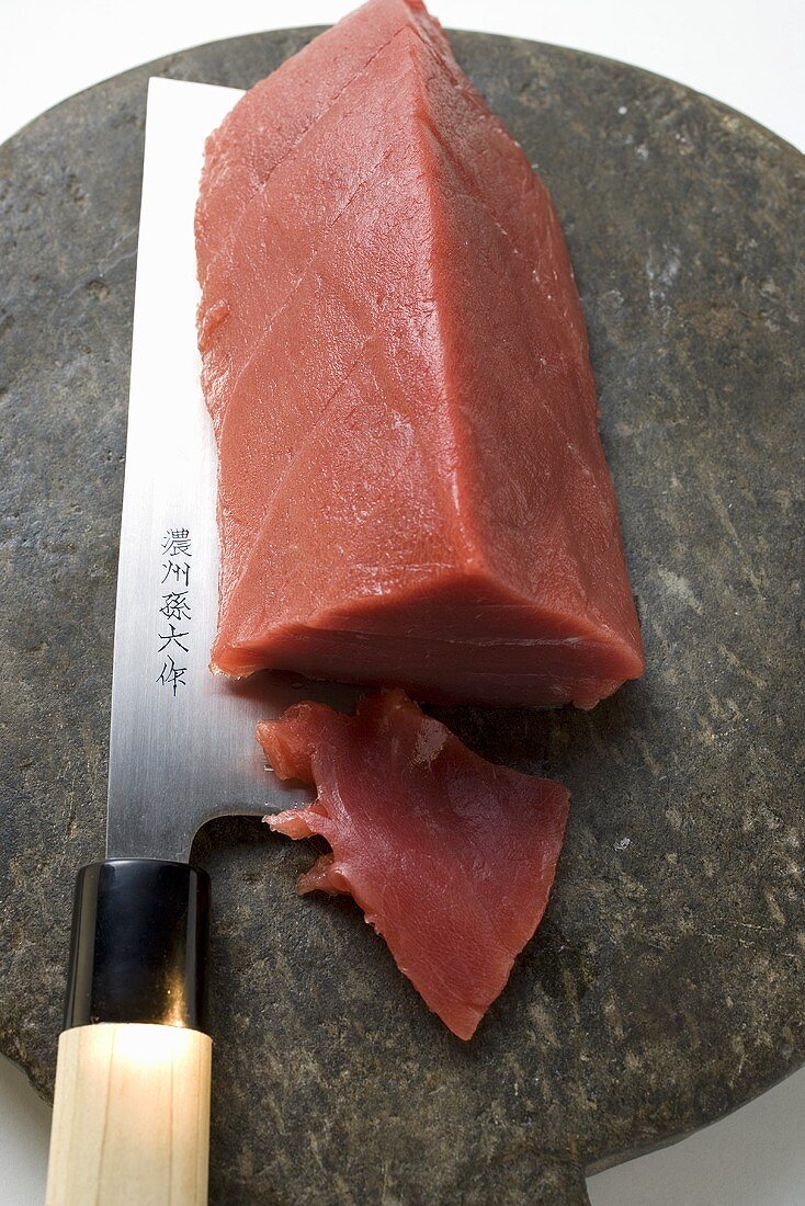 Tuna fillet, a piece cut off, with Asian knife