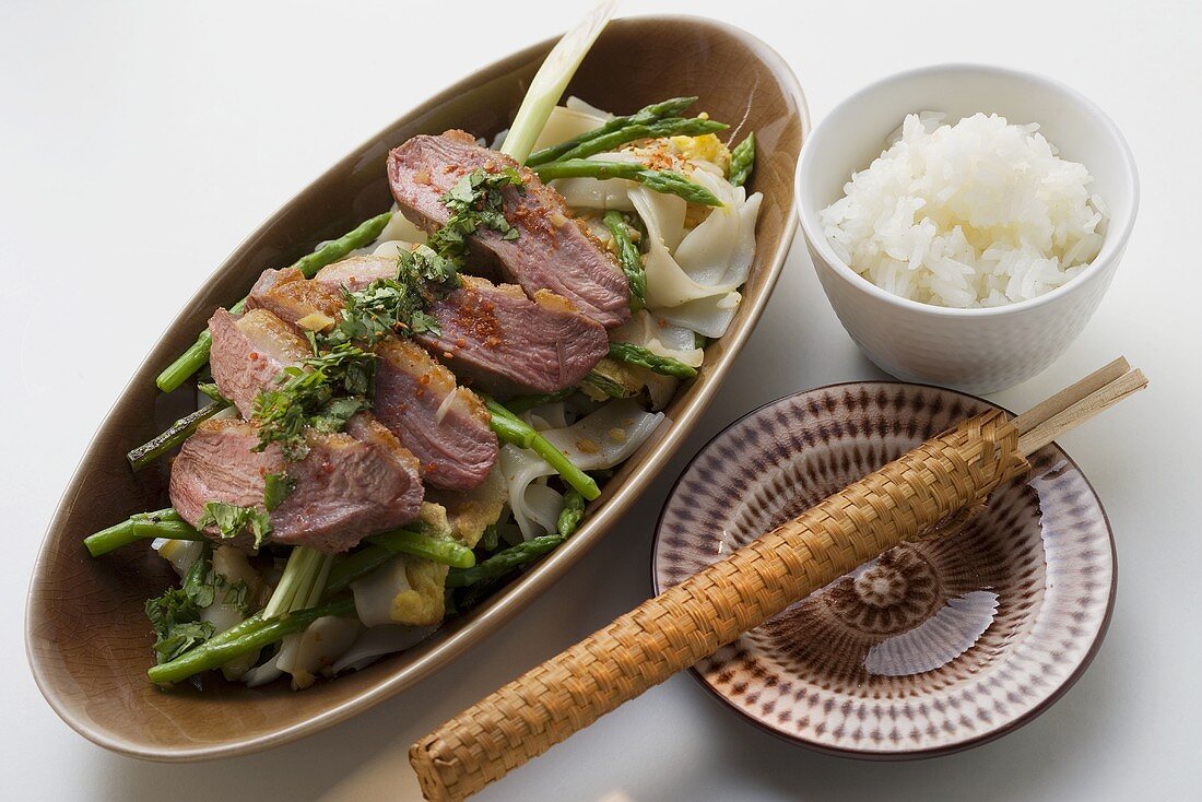 Duck breast on rice noodles with green asparagus, rice
