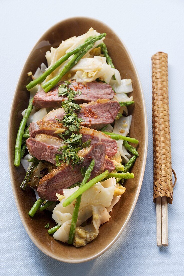 Duck breast on rice noodles with green asparagus