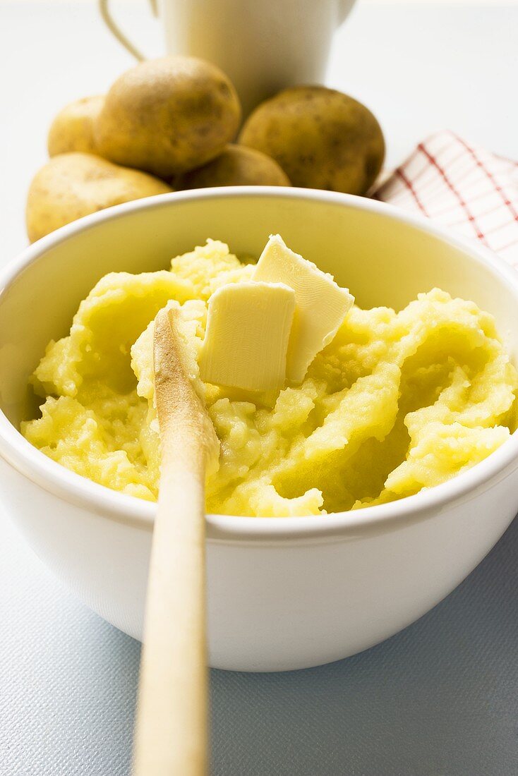 Kartoffelpüree mit Butter in Schüssel mit Kochlöffel