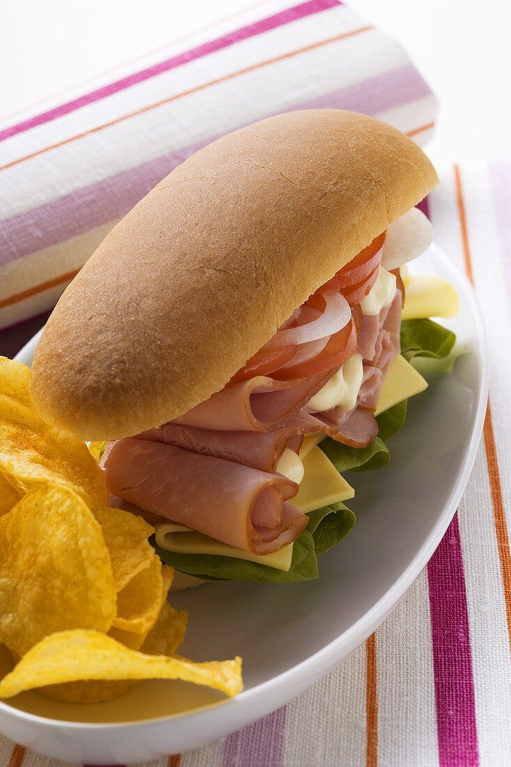 Ham, cheese, tomato and onion in sub sandwich with crisps