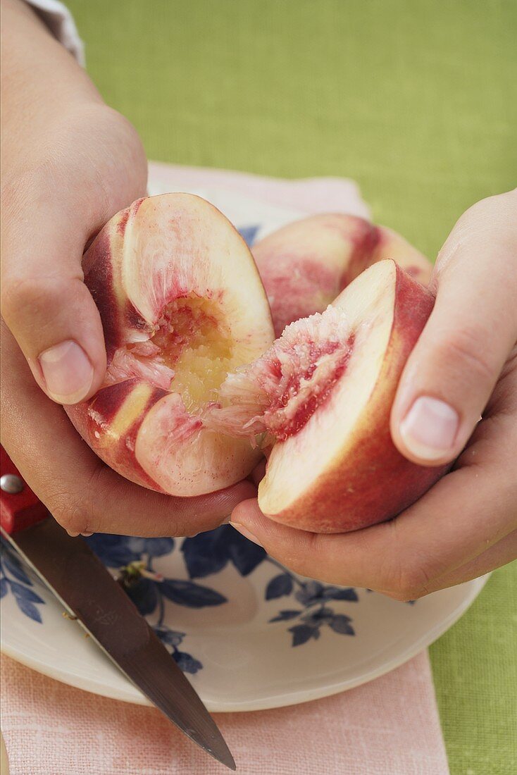 Hände halbieren frischen Pfirsich