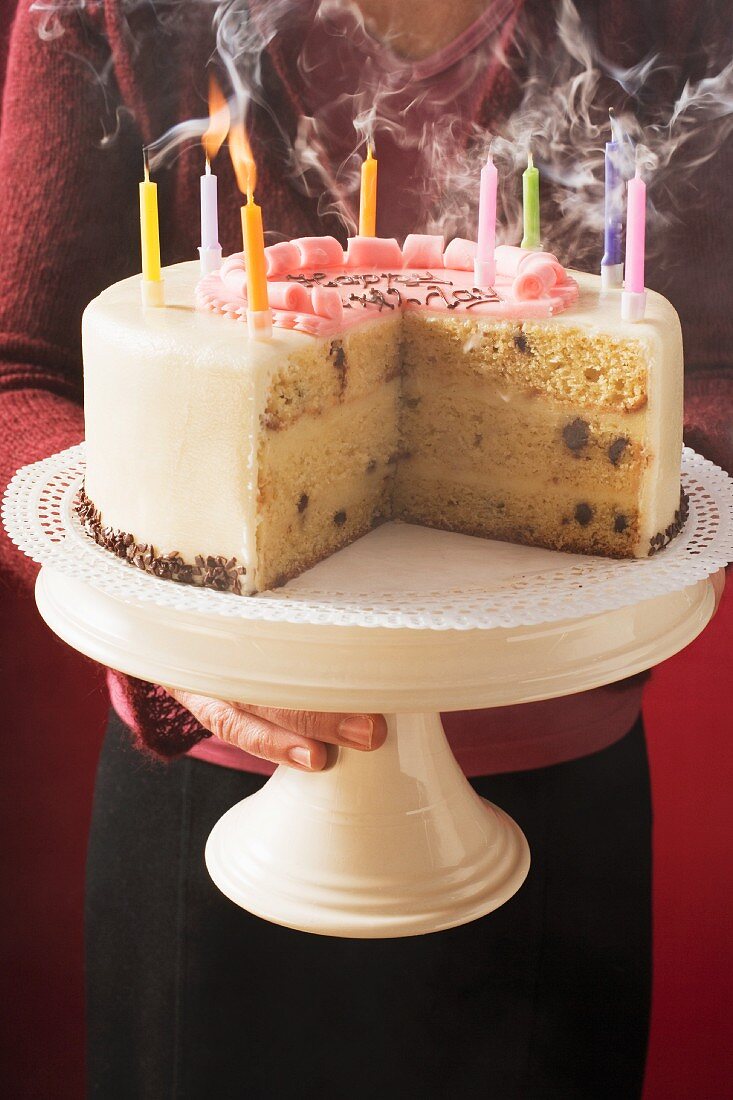 Woman serving birthday cake with blown-out candles