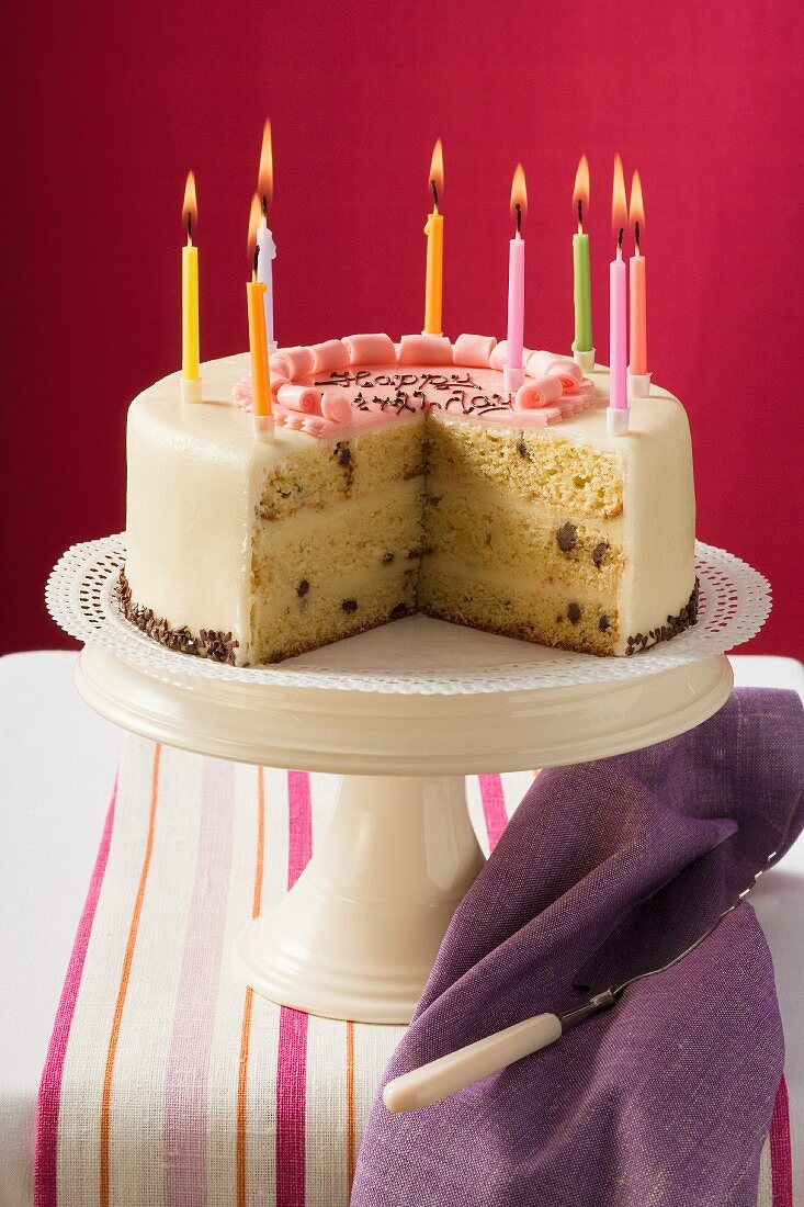 Birthday cake with burning candles, pieces taken