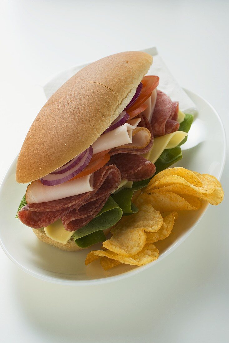 Sandwich mit Salami, Schinken, Käse, Gemüse und Chips