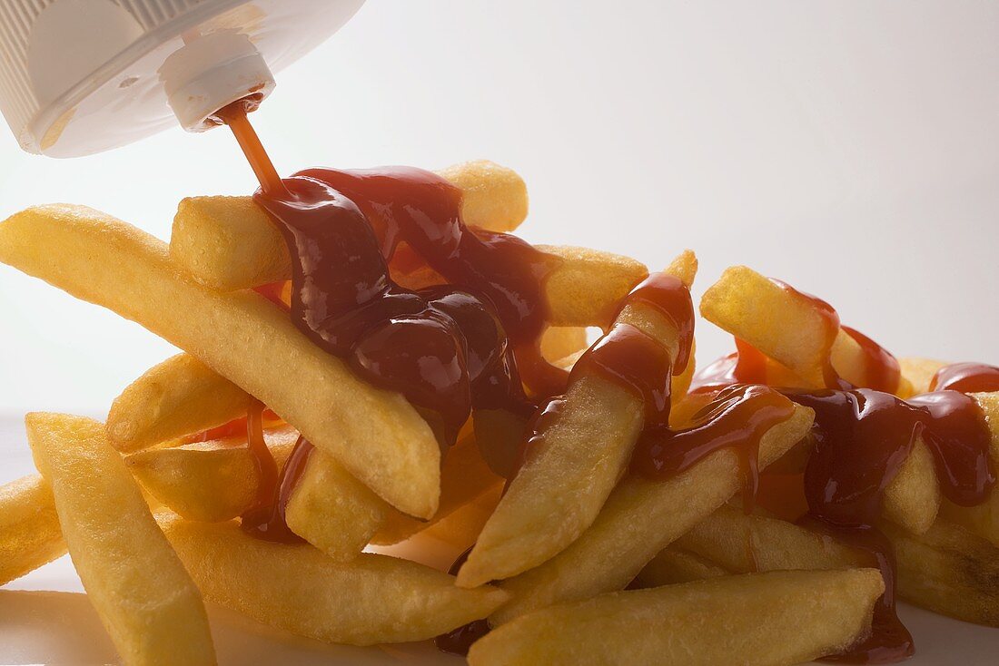 Squirting ketchup from a bottle onto chips