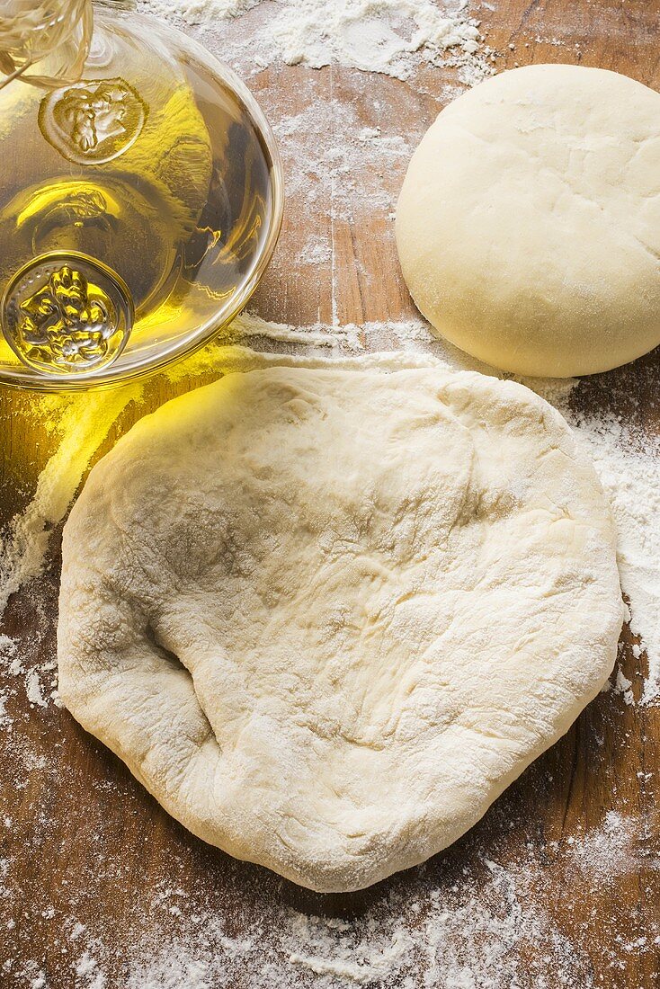 Uncooked dough, rolled out and in a ball, olive oil